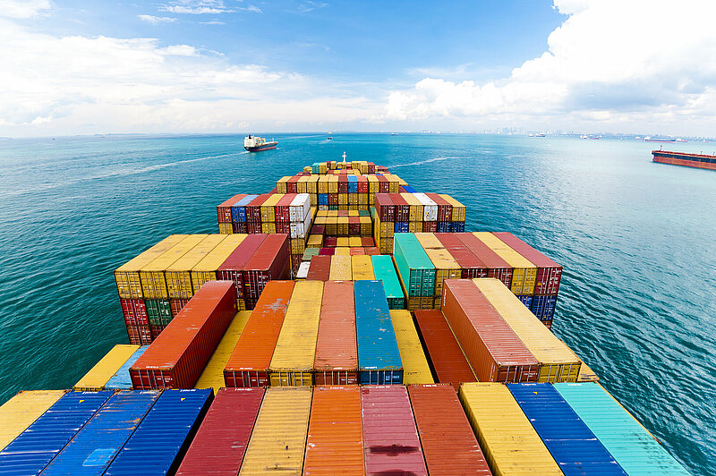 Container ship carrying multicolored freight containers across the ocean, symbolizing global shipping and 3PL logistics services.